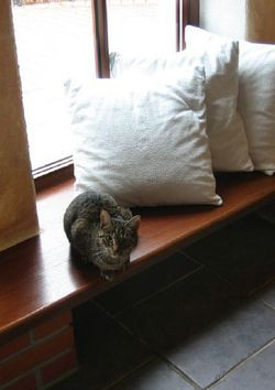 Niski parapet-siedzisko, który ciągnie się pod trzema widokowymi witrynami przez całą szerokość obniżonego o dwa schodki salonu