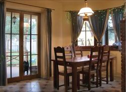 Jadalnia w dużym wykuszu z widokiem na sosny, oddzielona od nieurządzonej jeszcze kuchni surowym ceglanym murkiem