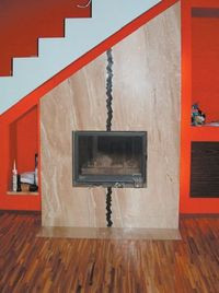 Kominek umieszczony pod schodami - na ścianach ognista czerwień