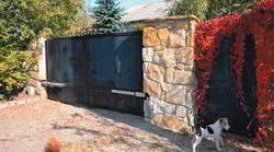 Dom stoi za metalową bramą i furtką