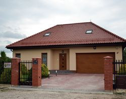 Dom ma prostą bryłę i czterospadowy dach pokryty dachówką ceramiczną. W obawie przed zaburzeniem proporcji bryły, jego właściciele nie podnieśli ścianek kolankowych. Nie żałują tego, choć pan Marcin jest wysoki i trudno mu poruszać się pod skośnymi ścianami na poddaszu