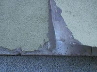 Na wysokości cokołu, tynk z siatką zbrojącą odkleja się całymi fragmentami