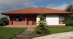 Ozdobą parterowego domu są narożne okna w pokojach prywatnych, klinkierowe elewacje przy głównym wejściu i na tarasie oraz rozłożysty łamany dach z ceramiczną dachówką. Kilka z tych elementów zaprojektowali autorzy gotowego projektu, kilka dodali właściciele