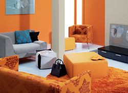 Jasna szarość uspokaja pomarańcz na tyle, że wzorzyste obicie kanapy subtelnieje