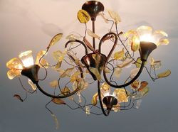 Każdy detal żyrandola Moorea wykonano ręcznie z przezroczystej barwionej żywicy oprawionej w patynowaną miedź