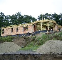 Widok z poziomu jeziorka na dom wznoszony w miejscowości Świdry