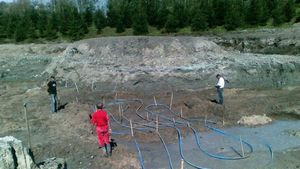 Układanie rurek kolektora sposobem meandrowym. Na drugim planie widoczna jest wyspa, kt&oacute;ra będzie leżała na środku jeziora