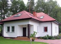 Dom o tradycyjnej kolorystyce i zwartej bryle dobrze wygląda na polanie wśr&oacute;d drzew