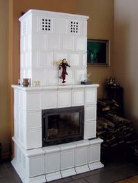 Kominek z żeliwnym wkładem obudowano cegłami szamotowymi i obłożono kaflami piecowymi, całość według projektu właścicielki