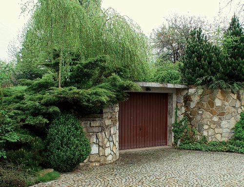 Garaż jest wkomponowany w niewielkie wzniesienie i otoczony wielopiętrową zielenią