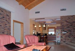 Salon łączy się z jadalnią, kuchnią oraz ogrodem zimowym. Ta część domu leży niżej niż pozostałe pomieszczenia w budynku