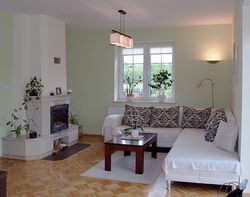 Kominek w saloniku nie ma dystrybucji ciepłego powietrza po całym budynku. A szkoda. Został wykończony płytami jasnego piaskowca i konglomeratu. Podłogę wykonano z solidnej dębowej klepki (z Hajnówki). Do zakątka pani domu wstawiła biały narożnik