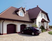 Dom od frontu. Właścicieli zachwyciła bryła budynku, zaproponowana w gotowym projekcie &#8211; dom wygląda solidnie i efektownie, a jednocześnie pasuje do podwarszawskiej wsi. Odpowiada im także wejście od strony północy oraz skierowanie wypoczynkowej strefy na południe