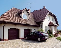 Dom od frontu. Właścicieli zachwyciła bryła budynku, zaproponowana w gotowym projekcie &#8211; dom wygląda solidnie i efektownie, a jednocześnie pasuje do podwarszawskiej wsi. Odpowiada im także wejście od strony północy oraz skierowanie wypoczynkowej strefy na południe