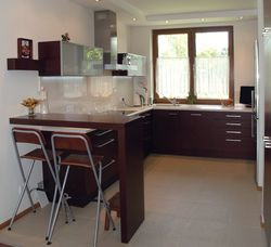 Kuchnia jest połączona z jadalnią. Meble wykonano na zamówienie, ale zaprojektowała je właścicielka. To ona zadecydowała również o zlikwidowaniu okna (w miejscu okapu), uznając, że inaczej nie zmieszczą się wszystkie potrzebne meble i sprzęty