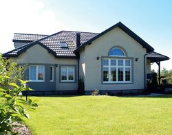 Elewację ogrodową ozdabia duże okno z łukiem, dające szeroki widok z salonu na ogród oraz wykusz powiększający małżeńską sypialnię. Udaną poprawką było zamontowanie drzwi tarasowych w jadalni, a nie jak to zaplanowano w salonie