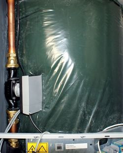 Po lewej stronie, na tle zaizolowanego zbiornika ciepłej wody użytkowej, widoczna jest pompa obiegowa górnego źródła