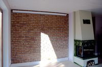 W salonie znajduje się ściana wymurowana z ręcznie formowanej cegły klinkierowej.