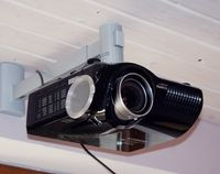 W salonie pod sufitem znajduje się projektor połączony z komputerem. Naprzeciw niego na ceglanej ścianie znajduje się zwijany ekran o przekątnej 3 m