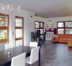 Nowocześnie urządzona przestrzeń jest przytulna, wesoła oraz pełna światła, które dociera do wnętrz przez duże okna. Najbardziej przeszklona jest elewacja ogrodowa. Stąd roztacza się widok na dużą działkę. Pomieszczenia dzienne można ogrzać żeliwną kozą