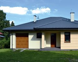 Niski parterowy budynek ma wymiary 14 × 16 m i ładnie dopasował się do wielkości i kształtu niedużej działki. Właściciele musieli jednak zrezygnować z garażu na dwa samochody, ponieważ nie zmieścił się na posesji. W przyszłości być może powstanie wiata na drugi samochód. Zaletą domu jest zadaszone wejście