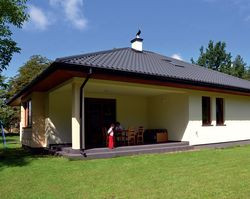 Właściciele szukali projektu z zadaszonym tarasem i cieszą się, że się to udało. Na tarasie spędzają naprawdę dużo czasu. W lecie to dodatkowy pokój. Posadzka, wykończona gresem w szarym kolorze, nawiązuje do koloru dachu. Długi okap chroni przed deszczem