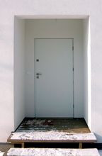 W elewacji budynku znajduje się niewielka wnęka, w której usytuowane są drzwi. Ma ona, między innymi, tę ważną zaletę, że w czasie deszczu pozwala poszukać kluczy do domu bez konieczności moknięcia lub wykonywania ekwilibrystyki z parasolem