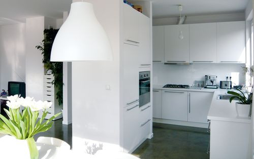 Salon jest częściowo oddzielony od kuchni ścianką, na której umieszczone zostały wysokie elementy umeblowania oraz sprzęt AGD