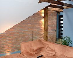 Po wykończeniu poddasza drewnianymi belkami oraz ceglaną ścianą powstało tam miejsce do oglądania telewizji. Niedługo zostanie tu zamontowana żeliwna koza. Obok znajduje się strefa prywatna właścicieli &#8211; duża łazienka i sypialnia z garderobą. Sypialnie dziewczynek oraz gabinet znajdują się na parterze