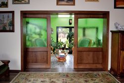 Szerokie przesuwane drzwi mają szyby, przez które do salonu wpada światło z oranżerii