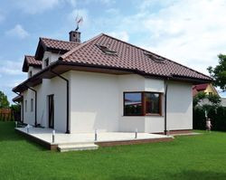 Łamany dach z lukarnami pokryto dachówką ceramiczną. Właściciele nie oszczędzali na ładnym i trwałym pokryciu budynku. Na parterze, przy salonie powiększyli taras, dzięki czemu stał się narożny i skierowany w stronę południa oraz zachodu. Po zakupie mebli ogrodowych zamierzają na nim jadać śniadania