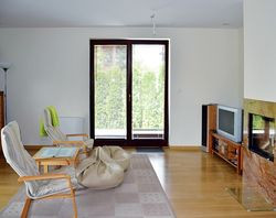 Rozłożysty dom zmieścił się na niedużej działce, choć właściciele powiększyli go o metr w stronę ogrodu wypoczynkowego. W wyniku tej zmiany w salonie uzyskali miejsce na kominek, o którym marzyli. Obudowa kominka wykonana została z kamiennej płyty. Podłogi wykończono dębowymi deskami