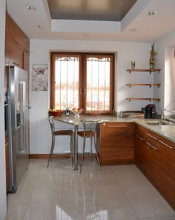 Kuchnia ma ponadczasową kolorystykę oraz zabudowę w kształcie litery „U”. Sprawdza się polerowany gres na podłodze i granit na blatach