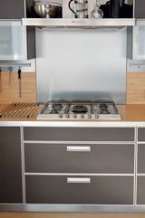 Materiały zabudowy kuchennej to: stal, szkło, laminowane fronty w kolorze grafitu i laminowane blaty w kolorze buku