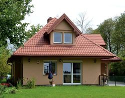 Działka ma wymiary 21 × 70 m. Właściciele mogli zabudować jedynie 20% powierzchni. Dom zbudowali w centrum posesji, by zyskać na jej zieleni i ciszy. Są z tego zadowoleni, choć utwardzenie drogi do garażu i wyłożenie jej kostką kosztowało 25 000 zł. Na okresowo mokrym gruncie było to niezbędne!