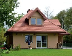 Działka ma wymiary 21 × 70 m. Właściciele mogli zabudować jedynie 20% powierzchni. Dom zbudowali w centrum posesji, by zyskać na jej zieleni i ciszy. Są z tego zadowoleni, choć utwardzenie drogi do garażu i wyłożenie jej kostką kosztowało 25 000 zł. Na okresowo mokrym gruncie było to niezbędne!