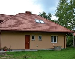 Tylna elewacja jest prostsza od frontowej. Marzeniem Uli i Rafała był dom z brązowym dachem i zielonymi elewacjami. Twarde warunki zabudowy zmusiły ich do wykonania dachu w czerwonym kolorze. Pokryli go blachodachówką. Na ścianach zastosowali tynk akrylowy w kolorze brzoskwiniowym