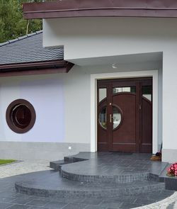 Wejście do budynku znajduje się pod okapem dachu. W drzwiach, zaprojektowano element powtarzający kształt okrągłego okna. Kolorystykę dziedzińca i schodów, wybrukowanych w dwóch kolorach, dopasowano do dachu i elewacji budynku