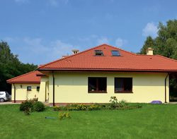 Jadalnię i salon oświetlają dwa duże okna. Rozciąga się z nich panorama na wypoczynkową część działki i duży trawnik, na którym chętnie bawią się dzieci. To jedna z zalet mieszkania pod miastem. Okna połaciowe w dachu oświetlają natomiast na poddaszu jedno wspólne pomieszczenie rodzinne z telewizorem