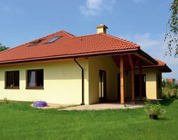 Z tyłu domu znajduje się taras wypoczynkowy. Docelowo ma zająć powierzchnię 40 m2. Połowa jest już zadaszona, bo dla właścicieli było to ważne kryterium wyboru projektu. Płyta tarasu znajduje się na poziomie trawnika i nie ma schodów. Jest również dostępna z salonu i pokoi prywatnych