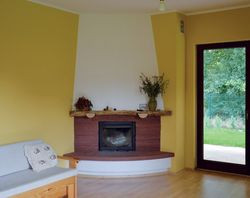 Wnętrza właściciele urządzali samodzielnie. W salonie zastosowali jasny parkiet z jesionu. Ściany z tynkiem cementowo-wapiennym pomalowali na ciepły słoneczny kolor. Kominek z systemem DGP, rozciągniętym po całym parterze, traktują jako wsparcie ogrzewania gazowym kotłem kondensacyjnym