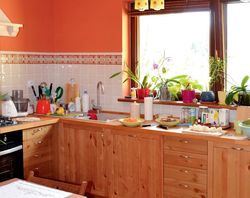 Kuchnię również doświetla duże okno. Daje widok na drogę i wjazd na działkę. Właściciele są z tego zadowoleni, podobnie jak z faktu, że pomieszczenie kuchenne jest oddzielone od jadalni i salonu. Komplet jadalny i szafki kuchenne wykonano z drewna