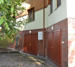 Przed frontem budynku rośnie rozłożysty orzech włoski, a wzdłuż zachodniej elewacji rząd świerków.