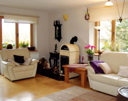 Salon znajduje się w dobudowanej części domu i ma wyjście na balkon. Podłogi z klepki zostały solidnie ułożone, dlatego nie rozsychają się nawet w pobliżu kozy.