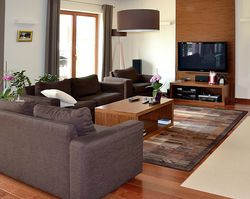 Właściciele lubią ładne drewniane podłogi, dlatego nawet w strefie dziennej ograniczyli powierzchnię posadzki z gresu z wodnym ogrzewaniem podłogowym. Na wszystkich kondygnacjach położyli drewno egzotyczne w ciepłym odcieniu brązu. Posadzki z matowego gresu mają beżowy kolor