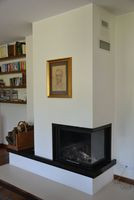 Kominek obudowany czarnym marmurem znajduje się w centrum parteru. Nie ma systemu DGP, więc ciepło rozchodzi się z niego grawitacyjnie. Właściciele kupili żeliwny wkład kominkowy z narożną szybą, aby ogień widoczny był z salonu i z jadalni