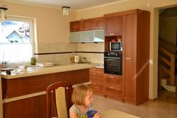 Szafki kuchenne wykonano na zamówienie. Mają fronty wykończone drewnianym fornirem. Blaty z płyt MDF. Małgosia i Tomasz są zadowoleni, że między kuchnią i jadalnią zastosowali bufet. Zasłania kuchenny nieład, ale nie zabiera światła i przestrzeni