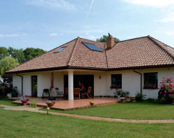 Elewacja wypoczynkowa sąsiaduje z dużym trawnikiem i ogrodem ozdobnym, o którym marzyła właścicielka. Widok na ogród od strony wnętrz umożliwiają duże okna i przesuwne drzwi tarasowe. Trójwarstwowe ściany otynkowano zmywalnym tynkiem akrylowym w kolorze kremowym, pasującym do cieniowanej dachówki