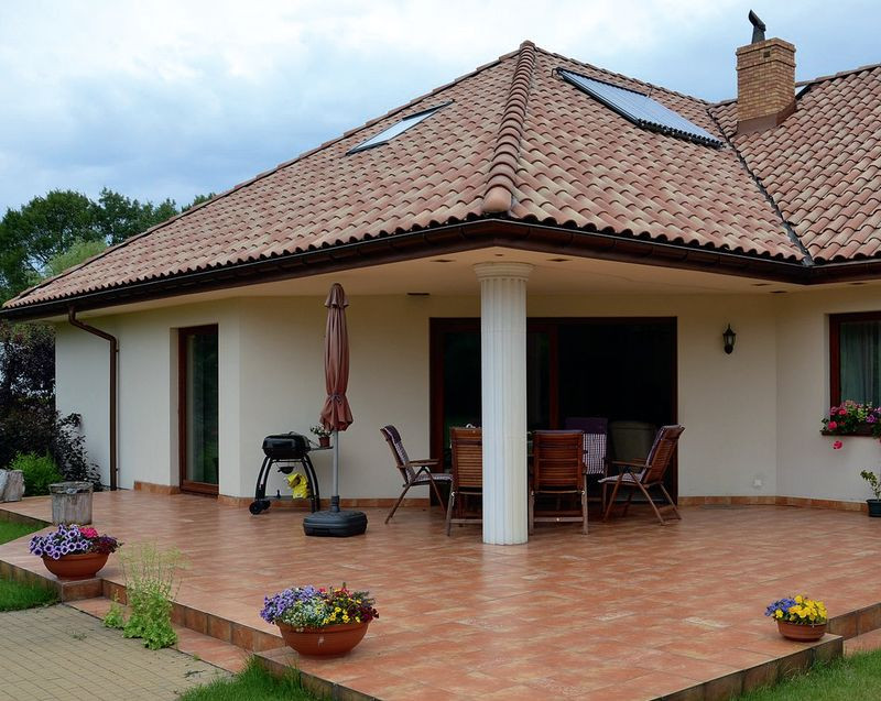 Zaletą domu jest częściowo zadaszony taras o powierzchni 40 m2. Na fragmencie płyty, osłoniętej wysuniętym dachem, latem stoi komplet mebli ogrodowych. Natomiast na nasłonecznionej części płyty podczas upałów rozkłada się basen, chroniąc trawnik przed zniszczeniem