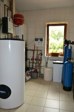 Pomieszczenie techniczne zajmuje powierzchnię 8,7 m2. Mieści urządzenia grzewcze, które dobrali pierwsi właściciele domu – m.in. kondensacyjny kocioł na gaz z sieci, wolno stojący zasobnik c.w.u. o poj. 300 l, elementy instalacji solarnej opartej na kolektorach próżniowych. Delfina i Andrzej zamontowali tu natomiast pralkę oraz rozbudowaną stację uzdatniania wody z przydomowej studni z filtrami mechanicznymi, kolumnami pozbawiającymi wodę nadmiaru żelaza i manganu, zmiękczaczem wody